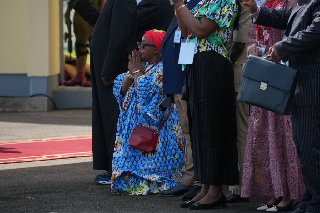 A woman kneels in prayer as Pope Leo XIV arrives at Yaounde-Nsimalen International Airport, Cameroon, Wednesday, April 15, 2026, on the third day of an 11-day apostolic journey to Africa. (AP Photo/Andrew Medichini)
