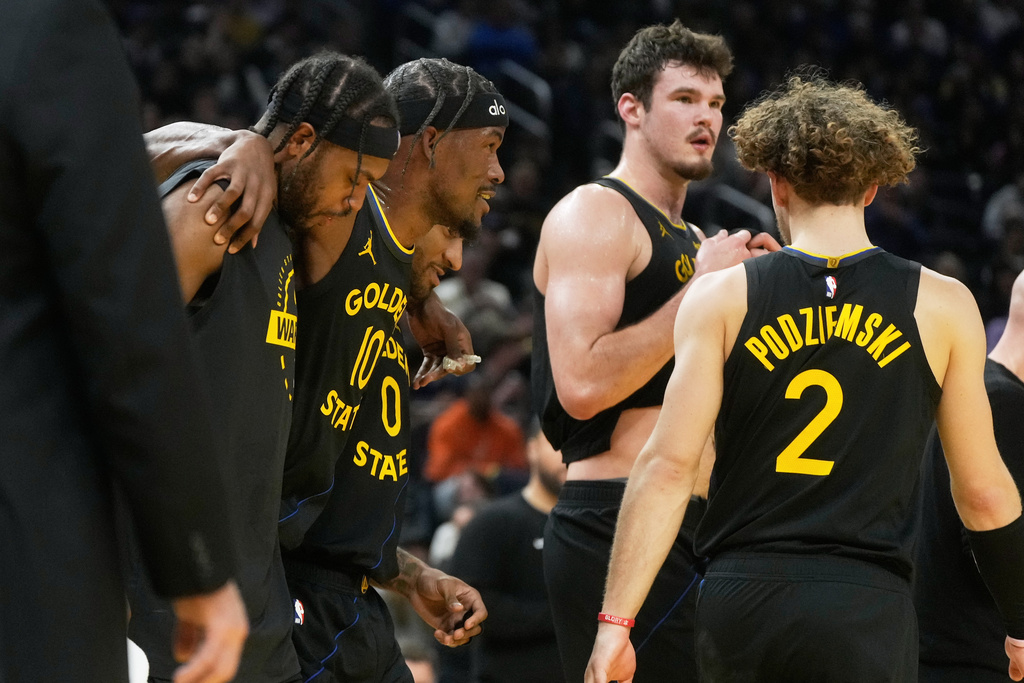 Golden State Warriors forward Jimmy Butler III, second from left, is helped off the floor by teammates during the second half of an NBA basketball game against the Miami Heat in San Francisco, Monday, Jan. 19, 2026. (AP Photo/Jeff Chiu)