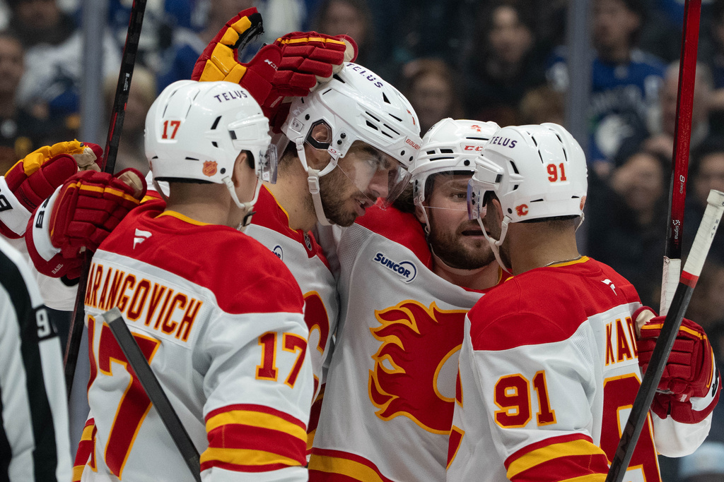 Calgary Flames' Kevin Bahl (7) celebrates his goal against the Vancouver Canucks with Yegor Sharangovich (17), Rasmus Andersson (4) and Nazem Kadri (91) during second period of an NHL game in Vancouver, British Columbia, on Sunday, Nov. 23, 2025. (Ethan Cairns/The Canadian Press via AP)