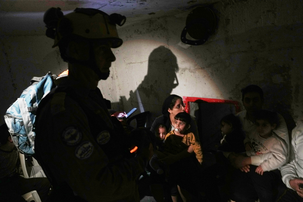 Israel's rescue teams and residents take shelter as sirens sounds next to a site struck by an Iranian missile in Bnei Brak, Wednesday, April 1, 2026. (AP Photo/Oded Balilty)