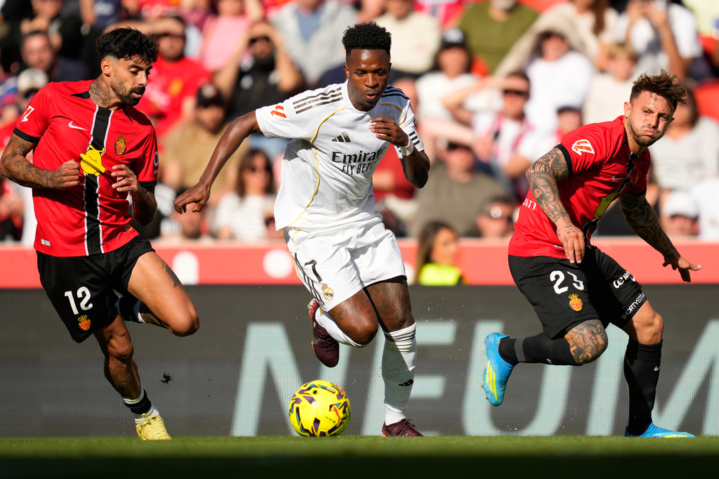 Real Madrid's Vinicius Junior in action betweem Mallorca's Samu Costa, left, and Pablo Maffeo during a La Liga soccer match between Mallorca and Real Madrid in Palma de Mallorca, Spain, Saturday, April 4, 2026. (AP Photo/Jose Breton)