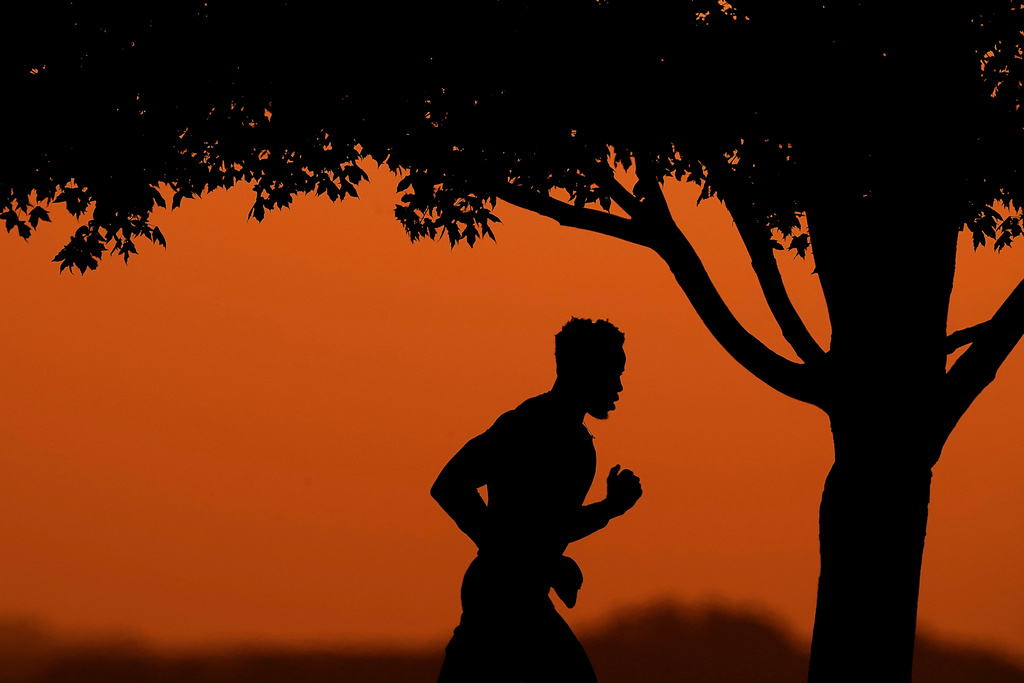 FILE - A man is silhouetted against the sky at sunset as he jogs in a park at the close of a hot summer day, Aug. 1, 2022, in Kansas City, Mo. (AP Photo/Charlie Riedel, File)