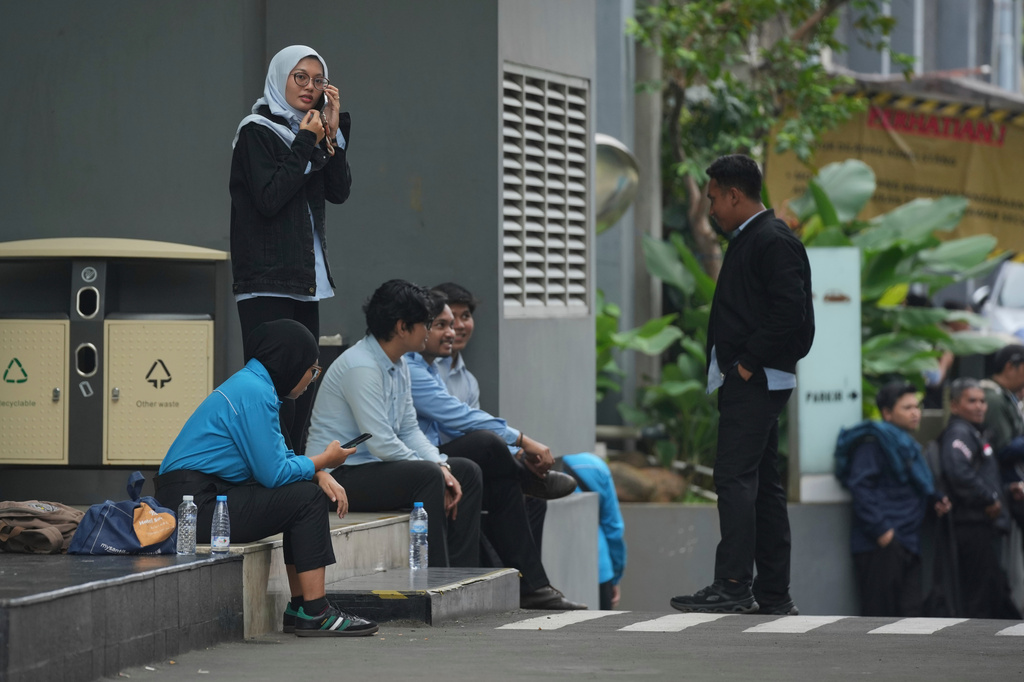 Employees wait outside the office of the National Nutrition Agency as it is being searched by prosecutors, in Jakarta, Indonesia, Wednesday, June 3, 2026. (AP Photo/Dita Alangkara)