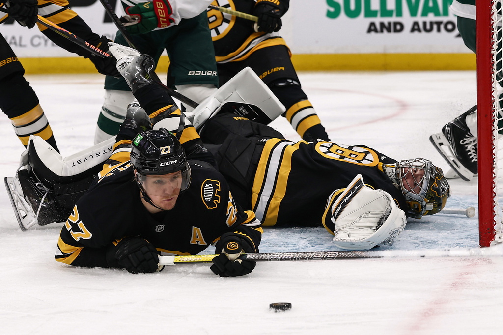 Boston Bruins defenseman Hampus Lindholm (27) and goaltender Jeremy Swayman, right, watch the puck near the crease during the second period of an NHL hockey game against the Minnesota Wild, Saturday, March 28, 2026, in Boston. (AP Photo/Winslow Townson)