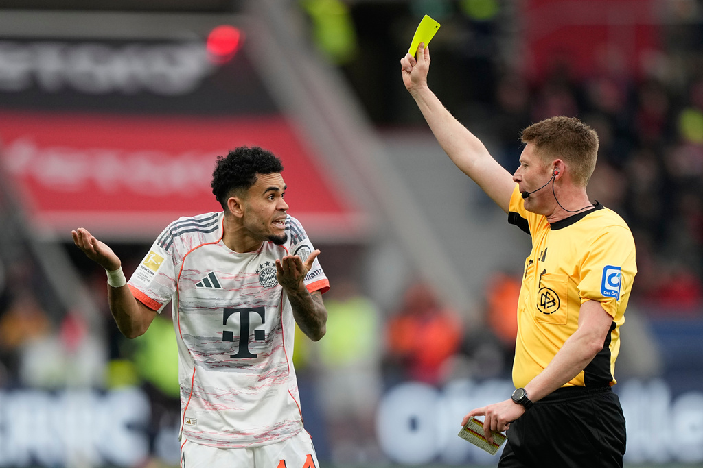 Referee Christian Dingert shows a yellow card to Bayern's Luis Diaz during a German Bundesliga soccer match between Bayer Leverkusen and Bayern Munich in Leverkusen, Germany, Saturday, March 14, 2026. (AP Photo/Martin Meissner)