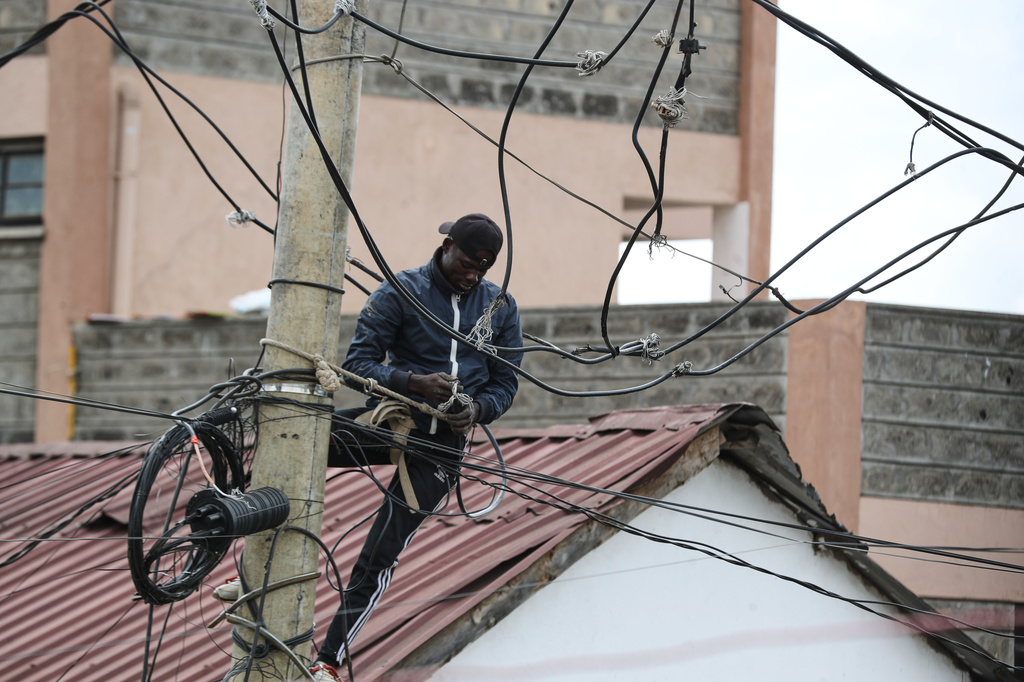 FILE -A man connects electric cables on a pole above the Kibera informal settlement in Nairobi, Kenya, March 31, 2026. (AP Photo/Henry Naminde, File)