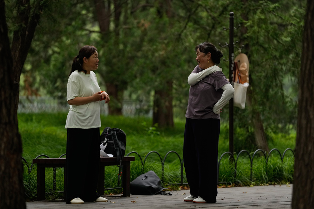 Ye Guirong, left, chats with Zu Hong after practicing Tai Chi at a park near the Temple of Heaven in Beijing, Thursday July 9, 2026. (AP Photo/Andy Wong)