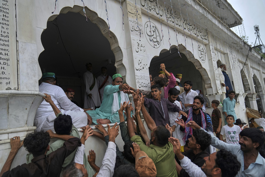 Devotees jostle to get free sweets as they attend celebrations of the three-day annual festival or 'Urs' of mystic and scholar, Hazrat Ali Hajveri, popularly known as Data Ganj Bakhsh at his shrine, in Lahore, Pakistan, Thursday, Aug. 14, 2025. (AP Photo/K.M. Chaudary)
