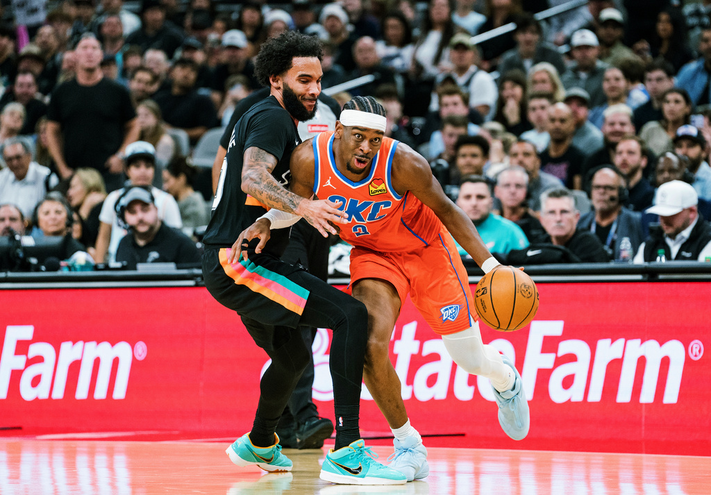 Oklahoma Thunder guard Shai Gilgeous-Alexander (2) dribbles against San Antonio Spurs forward Keldon Johnson (3) during the first half of an NBA basketball game in San Antonio, Tuesday, Dec. 23, 2025. (AP Photo/Rodolfo Gonzalez)
