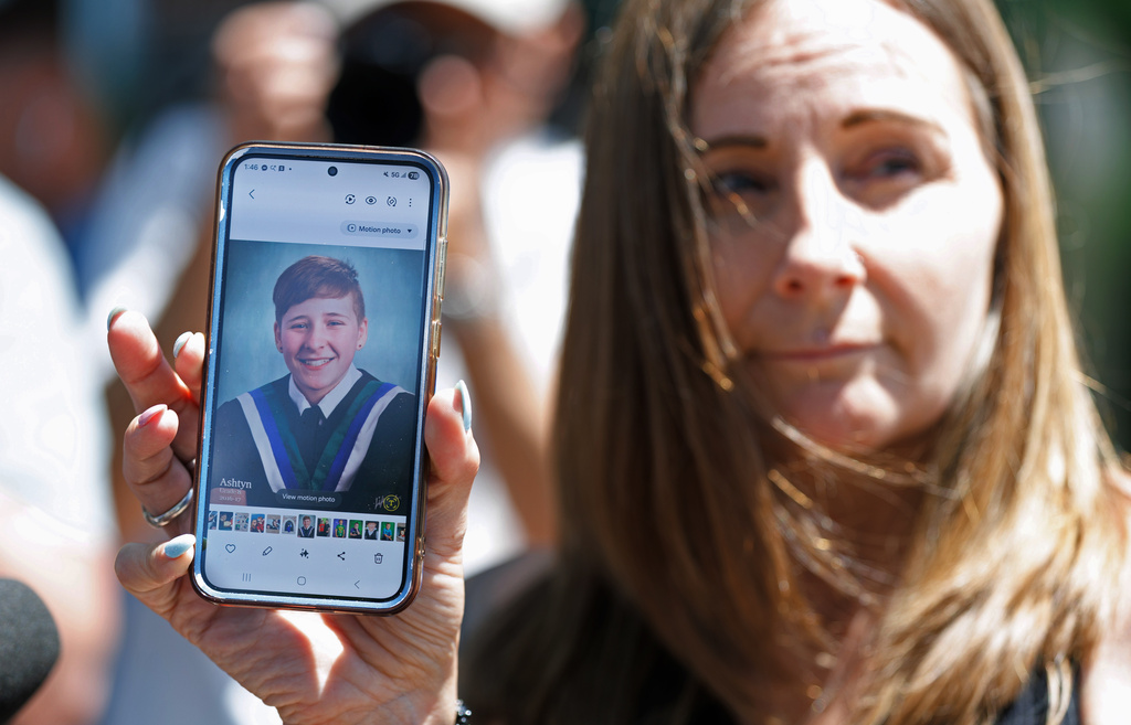 Kim Prosser holds a photo of her son Ashtyn outside the Ontario Court of Justice, Friday, May 29, 2026, in Newmarket, Ontario, after Kenneth Law pleaded guilty to 14 counts of counseling or aiding suicide, including the death of Prosser's son. (Christopher Drost/The Canadian Press via AP)