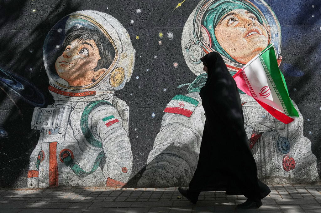 A woman walks past a mural depicting Iranian astronauts in space in Tehran, Iran, Wednesday, April 8, 2026. (AP Photo/Francisco Seco)