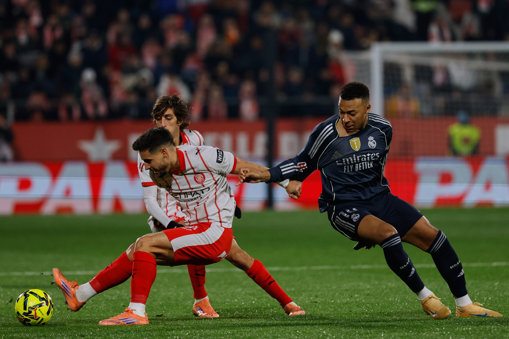 Girona's Ivan Martin, left, fights for the ball with Real Madrid's Kylian Mbappe during a Spanish La Liga soccer match between Girona and Real Madrid, in Girona, Spain, Sunday, Nov. 30, 2025. (AP Photo/Joan Monfort)