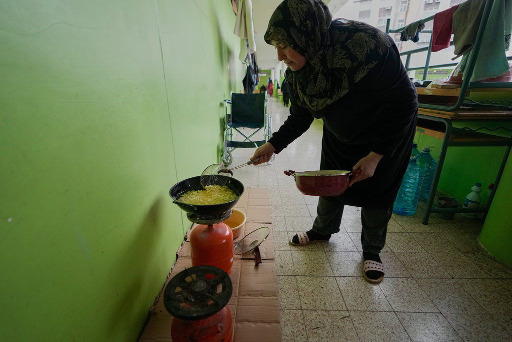 A displaced woman who fled Israeli strikes from south Lebanon, prepares food for Iftar, the Ramadan fast-breaking meal, at a school turned into a shelter, in the southern port city of Sidon, Lebanon, Saturday, March 14, 2026. (AP Photo/Mohammed Zaatari)