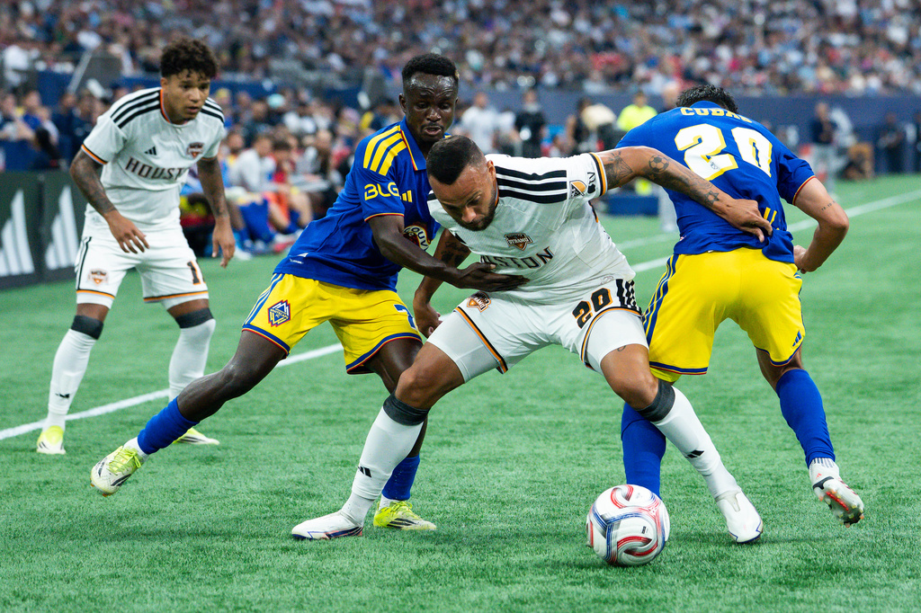 Houston Dynamo FC's Guilherme Santos, center, Vancouver Whitecaps' Cheick Sabaly, left, and Andres Cubas, right, vie for the ball during the first half of an MLS soccer match in Vancouver, B.C., on Wednesday, Aug. 19, 2026. (Ethan Cairns/The Canadian Press via AP)