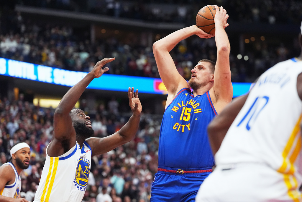 Denver Nuggets center Nikola Jokić (15) looks to shoot for a basket over Golden State Warriors forward Draymond Green (23) in the first half of an NBA Cup basketball game Friday, Nov. 7, 2025, in Denver. (AP Photo/David Zalubowski)