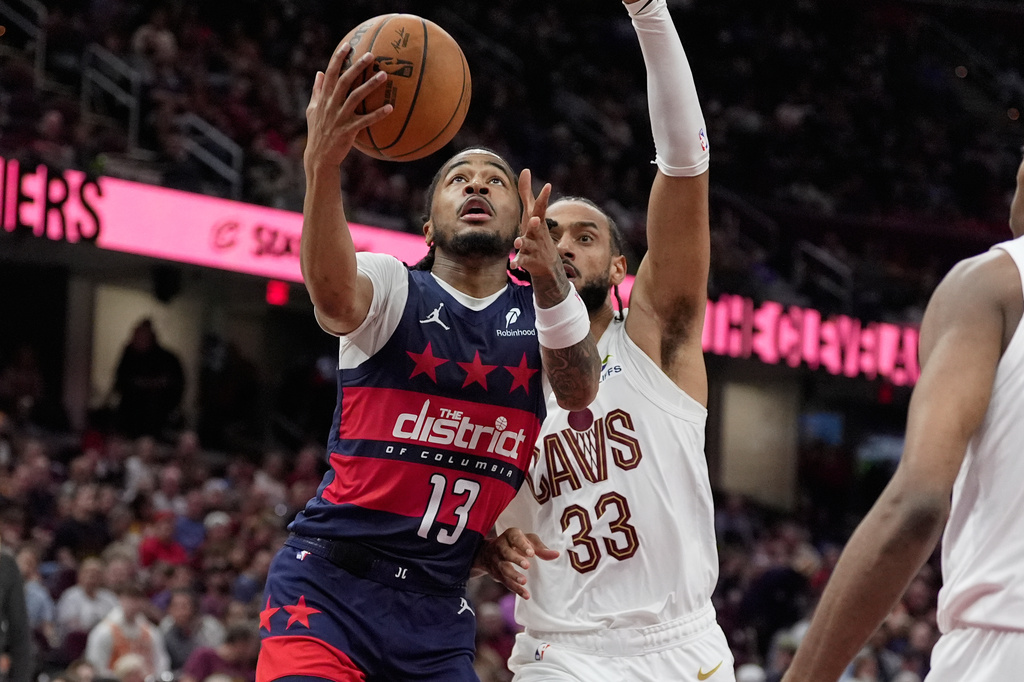 Washington Wizards guard Sharife Cooper (13) goes to the basket past Cleveland Cavaliers forward Olivier Sarr (33) in the second half of an NBA basketball game in Cleveland, Sunday, April 12, 2026. (AP Photo/Sue Ogrocki)