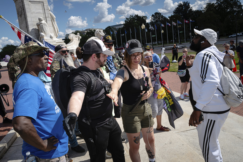 Protesters use their bodies to deescalate an argument with a counter-protester at Union Station, Monday, Sept. 1, 2025, in Washington. (AP Photo/Jon Cherry)