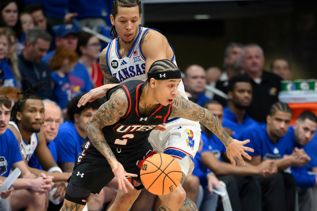 Utah guard Don McHenry (3) drives around Kansas guard Tre White during the first half of an NCAA college basketball game in Lawrence, Kan., Saturday, Feb. 7, 2026. (AP Photo/Reed Hoffmann)