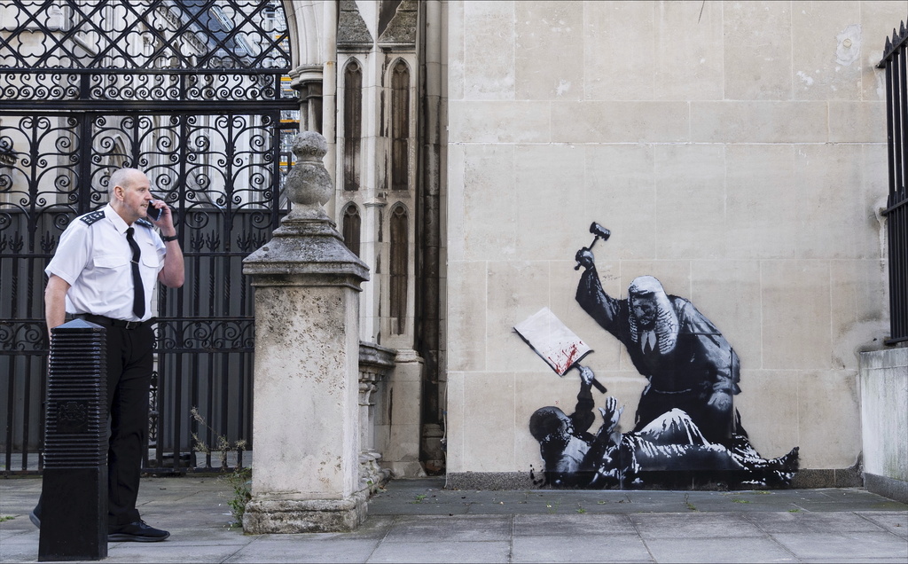 Undated photo released by Banksy of the new artwork by the artist which portrays a judge beating a protester with a gavel at the Royal Courts of Justice in London. (Banksy via AP)
