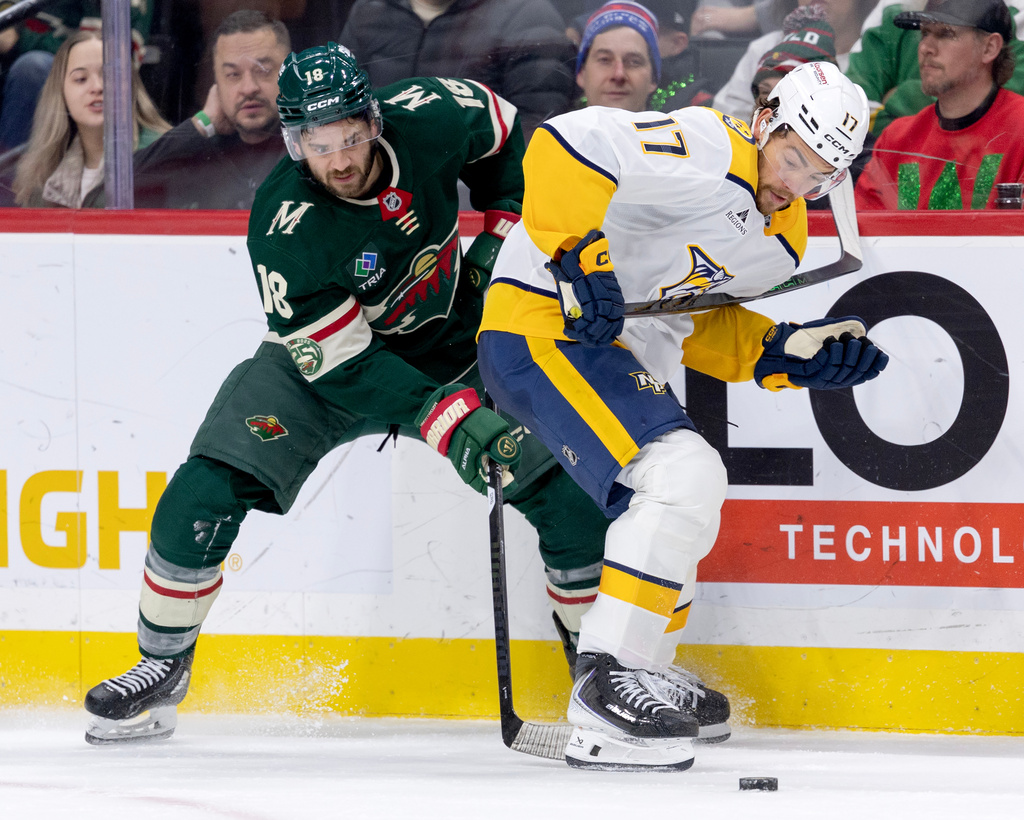 Minnesota Wild's Vinnie Hinostroza (18) and Nashville Predators Tyson Jost (17) battle for the puck in the second period of an NHL hockey game against the Minnesota Wild, Tuesday, Dec. 23, 2025, in St. Paul, Minn. (Carlos Gonzalez/Star Tribune via AP)