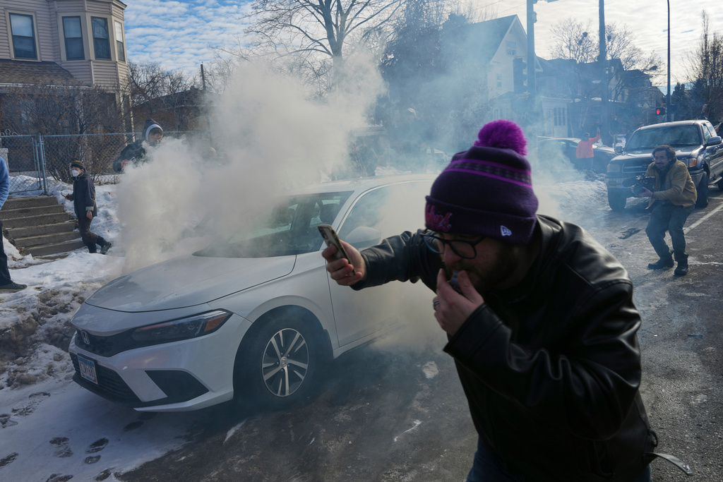 Protesters try to avoid tear gas dispersed by federal agents, Monday, Jan. 12, 2026 in Minneapolis (AP Photo/Adam Gray)