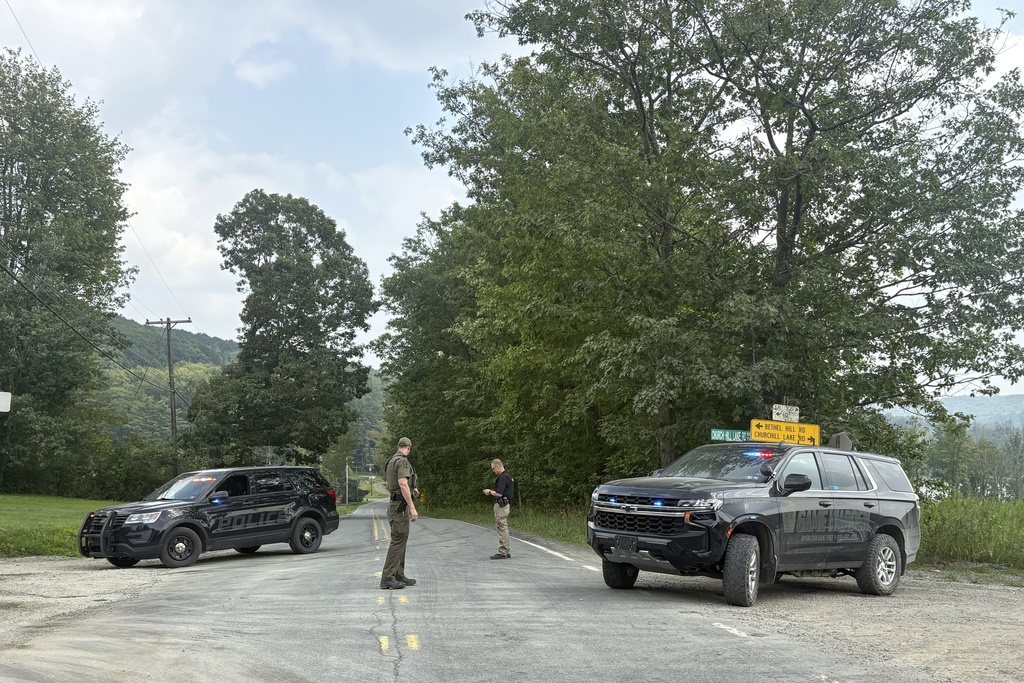 Police officers block the street leading to where two Pennsylvania state troopers were ambushed and shot Thursday, Aug. 7, 2025, near the village of Thompson in Susquehanna County, Pa. (AP Photo/Aimee Dilger)