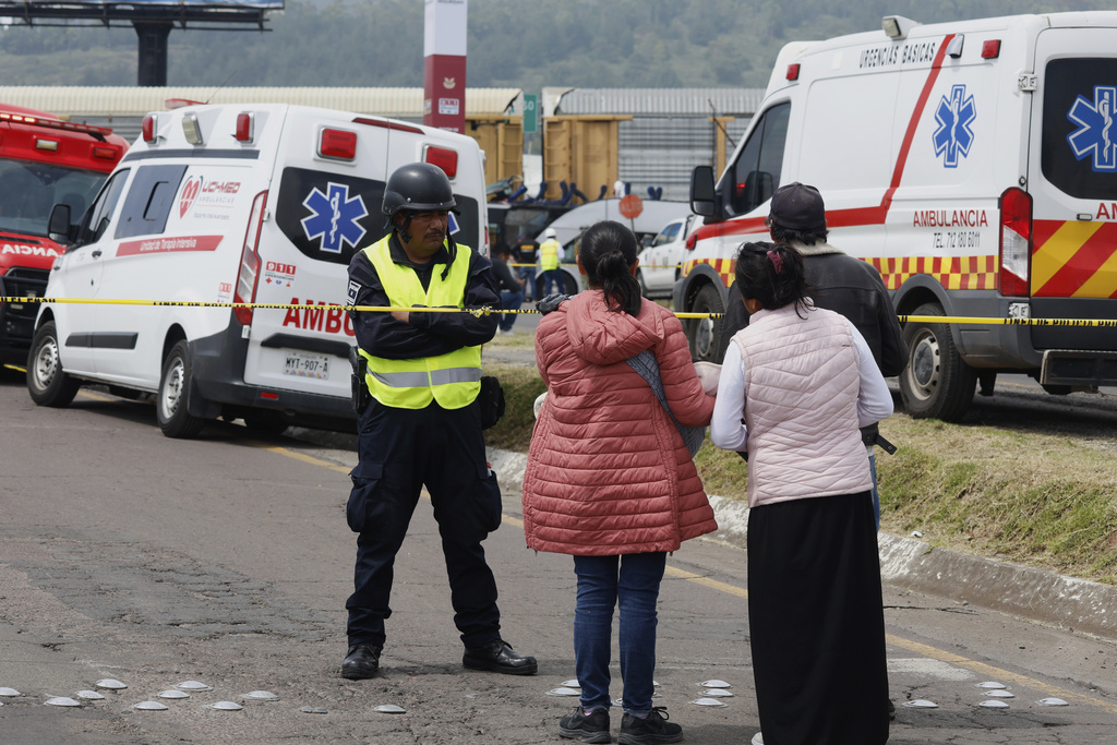 People watch rescue workers respond to a deadly accident where a freight train slammed into a double-deck bus in Atlacomulco, Mexico, Monday, Sept. 8, 2025. (AP Photo/Ramses Mercado Valdes)