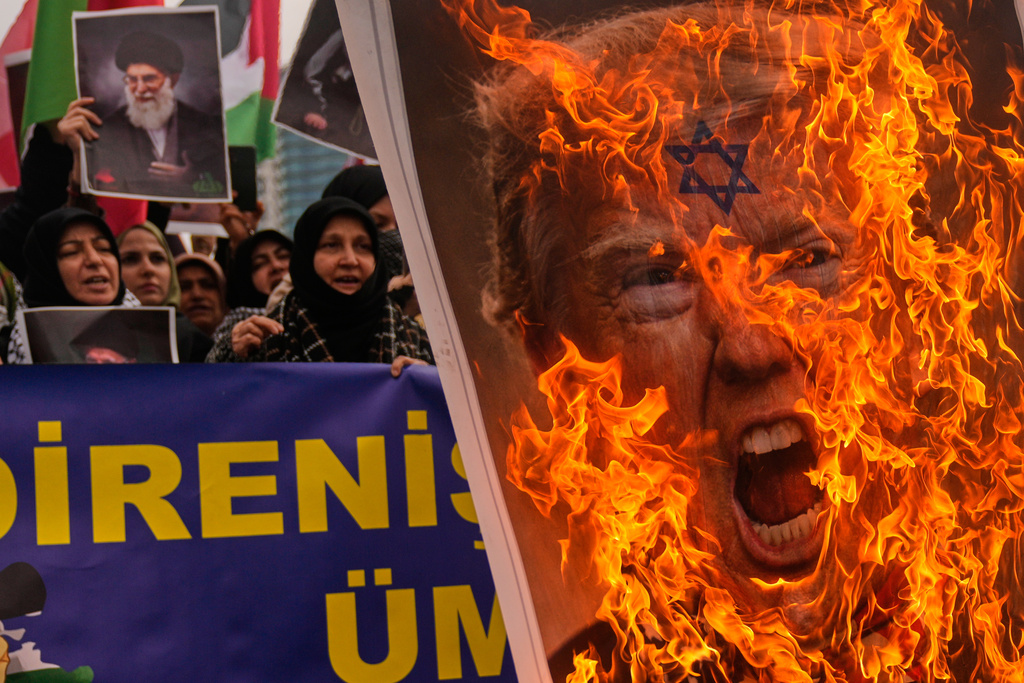 Demonstrators burn a picture of President Donald Trump during a protest outside the Israeli consulate in Istanbul, Sunday, March 1, 2026. (AP Photo/Khalil Hamra)