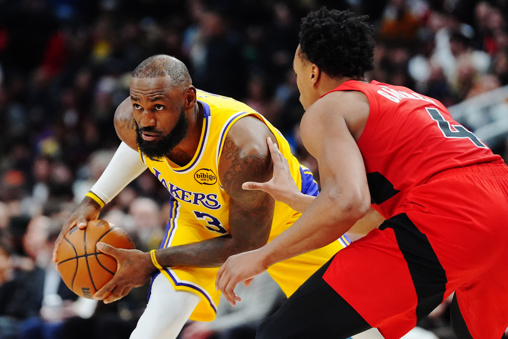 Los Angeles Lakers' LeBron James, left, is guarded by Toronto Raptors' Scottie Barnes (4) during second-half NBA basketball game action in Toronto, Thursday, Dec. 4, 2025. (Frank Gunn/The Canadian Press via AP)