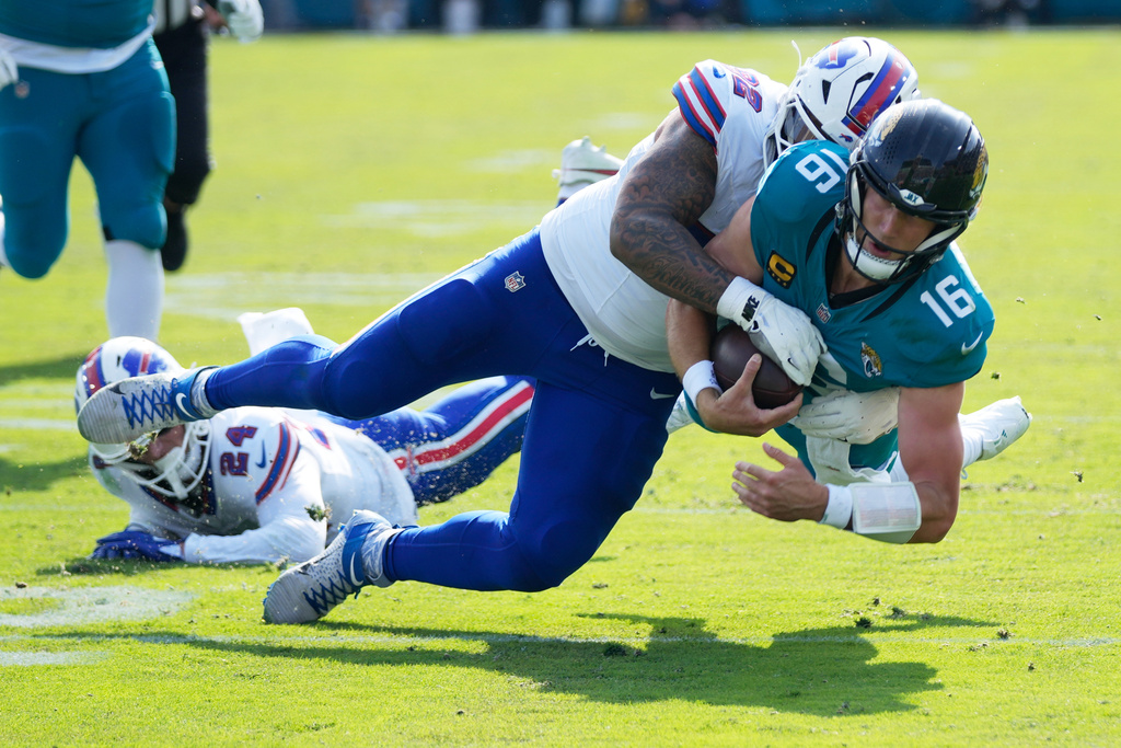 Jacksonville Jaguars quarterback Trevor Lawrence (16) is stopped by Buffalo Bills defensive tackle Daquan Jones (92) on a keeper during the first half of an NFL wild-card playoff football game Sunday, Jan. 11, 2026, in Jacksonville, Fla. (AP Photo/John Raoux)