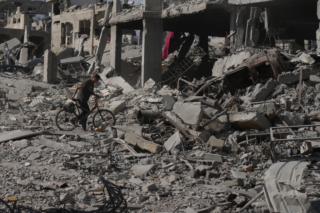A man pushes his bicycle through rubble in Gaza City, Sunday, Oct. 12, 2025, after Israel and Hamas agreed to a pause in their war and the release of the remaining hostages. (AP Photo/Jehad Alshrafi)