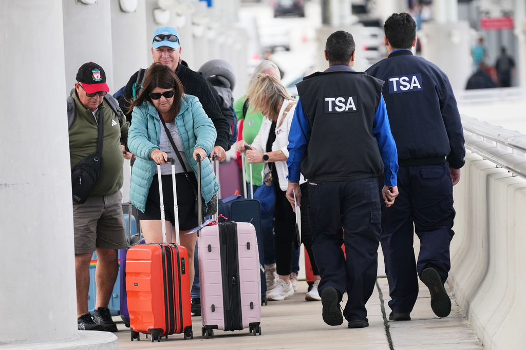 FILE - Travelers walk with their luggage past TSA agents at Fort Lauderdale-Hollywood International Airport, Nov. 13, 2025, in Fort Lauderdale, Fla. (AP Photo/Lynne Sladky, File)