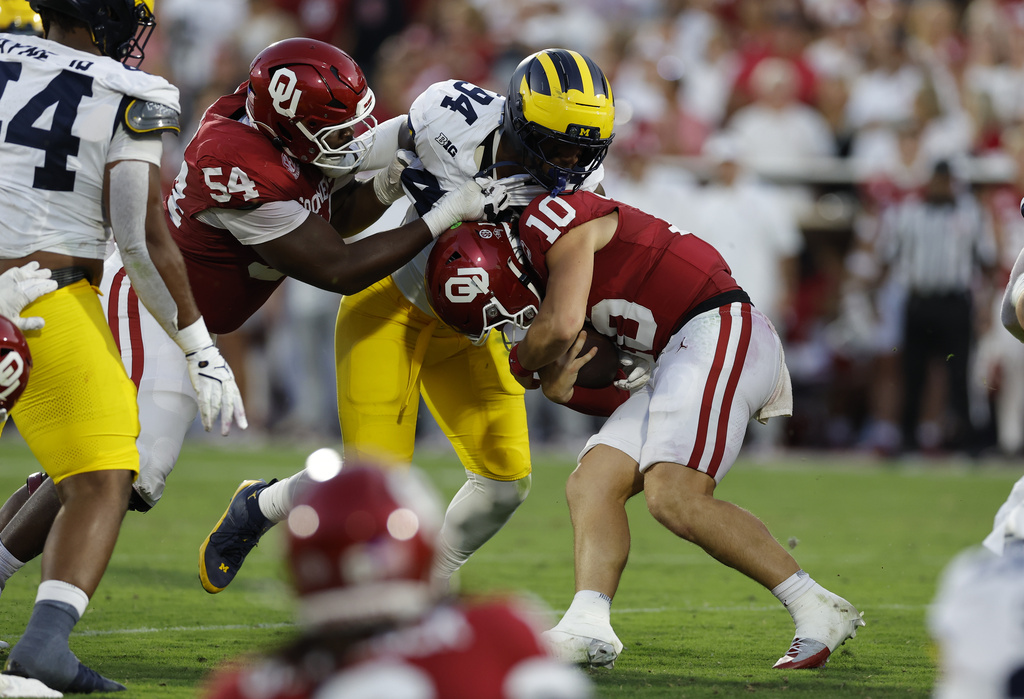 Oklahoma quarterback John Mateer (10) is tackled by Michigan edge Nate Marshall (94) during the first half of an NCAA college football game Saturday, Sept. 6, 2025, in Norman, Okla. (AP Photo/Alonzo Adams)