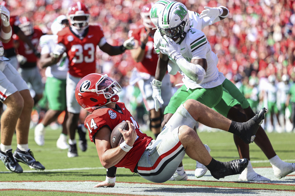 Georgia quarterback Gunner Stockton (14) scores a touchdown during the first half of an NCAA college football game against Marshall, Saturday, Aug. 30, 2025, in Athens, Ga. (AP Photo/Colin Hubbard)