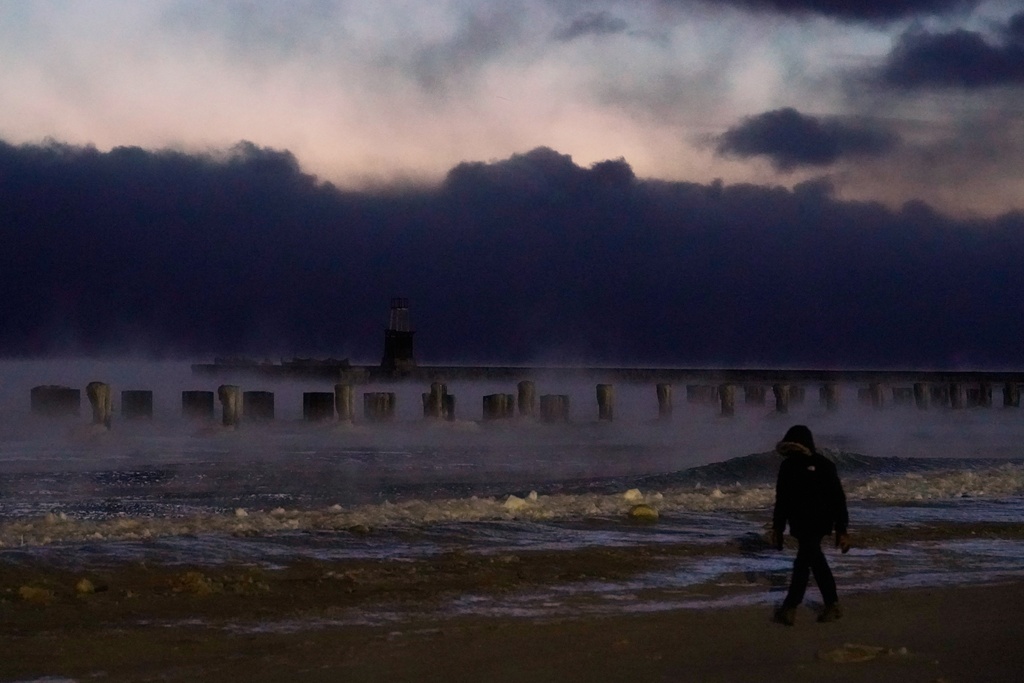 A person walks on an ice covered beach along the shore of Lake Michigan, Friday, Jan. 23, 2026, in Chicago. (AP Photo/Kiichiro Sato)