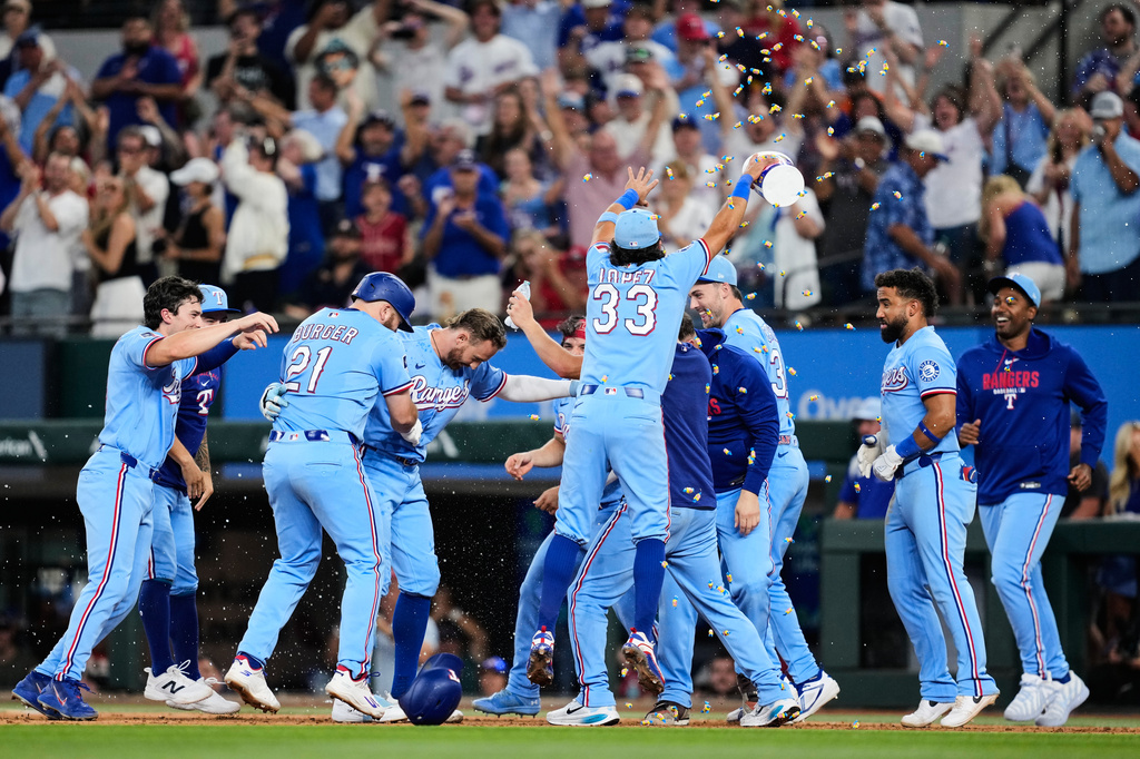 Texas Rangers' Brandon Nimmo, fourth from left, celebrates with the team after hitting a run-scoring single in the ninth inning of a baseball game against the Houston Astros in Arlington, Texas, Sunday, July 12, 2026. (AP Photo/Tony Gutierrez)
