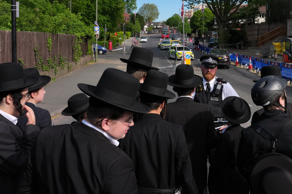 FILE - Members of the community watch as forensic officers search the area after two people were stabbed in the Golders Green neighborhood, that has a large Jewish community, in London, April 29, 2026. (AP Photo/Kin Cheung, File)