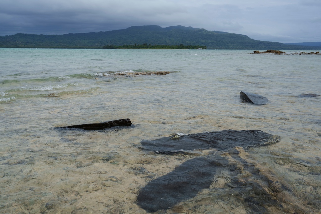 FILE - Gravestones sit submerged in water on Pele Island, Vanuatu, a country heavily affected by rising seas July 18, 2025. (AP Photo/Annika Hammerschlag, File)