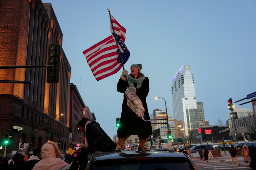 Teresa Hurst waves an upside-down American flag on top of a car during a rally against federal immigration enforcement on Friday, Jan. 23, 2026, in Minneapolis. (AP Photo/Angelina Katsanis)