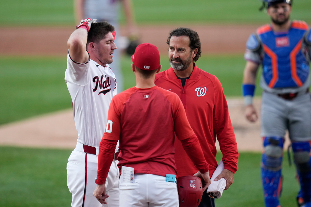 Washington Nationals' Jacob Young, left, is checked by manager Blake Butera, center, and head athletic trainer Dale Gilbert, third from left, after he was hit by a pitch during the second inning of a baseball game against the New York Mets, Monday, May 18, 2026, in Washington. (AP Photo/Jess Rapfogel)