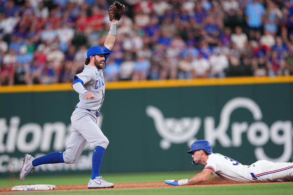 Chicago Cubs shortstop Dansby Swanson, left, reaches for the throw from catcher Carson Kelly as Texas Rangers' Evan Carter, right, steals second base during the second inning of a baseball game Saturday, May 9, 2026, in Arlington, Texas. (AP Photo/Julio Cortez)