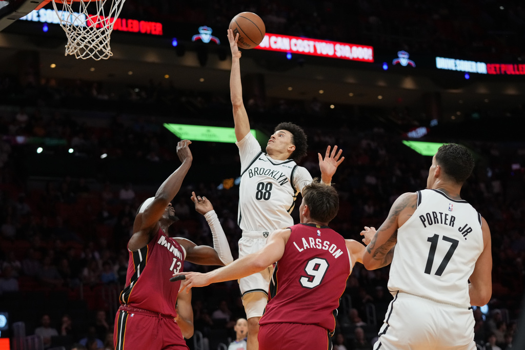 Brooklyn Nets guard Nolan Traore (88) goes to the basket as Miami Heat center Bam Adebayo (13) and guard Pelle Larsson (9) defend during the first half of an NBA basketball game, Thursday, March 5, 2026, in Miami. (AP Photo/Lynne Sladky)