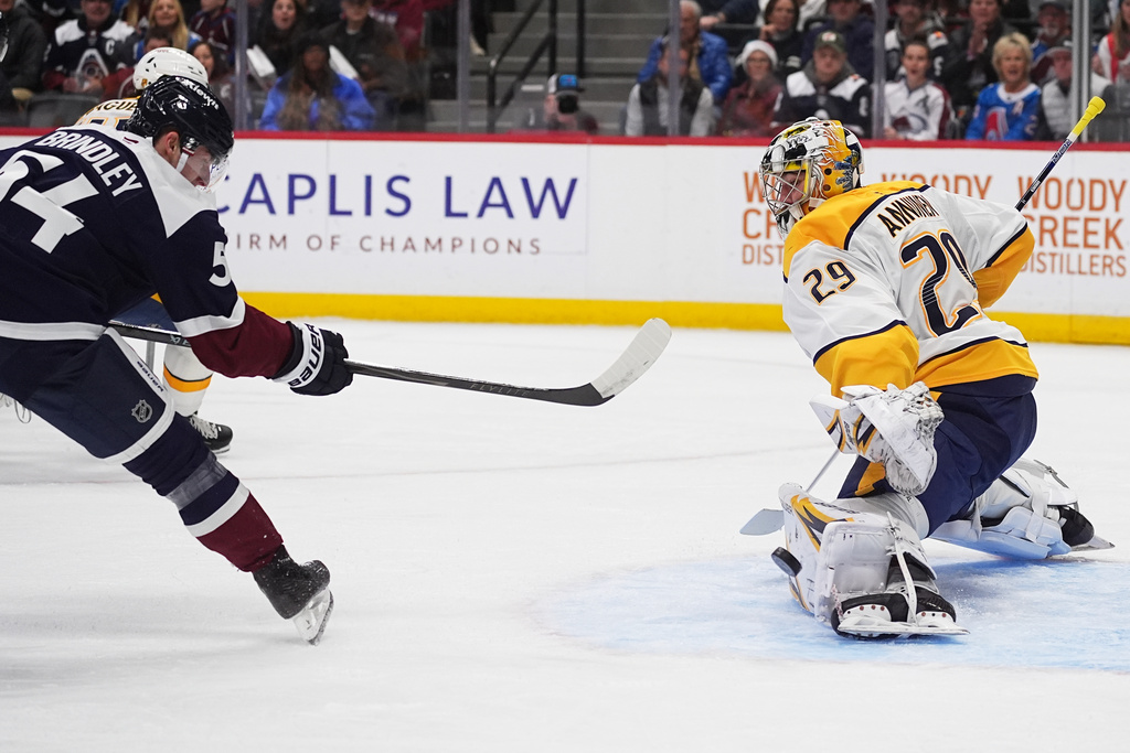 Colorado Avalanche center Gavin Brindley, left, has his shot deflected off the pad of Nashville Predators goaltender Justus Annunen in the first period of an NHL hockey game, Saturday, Dec. 13, 2025, in Denver. (AP Photo/David Zalubowski)