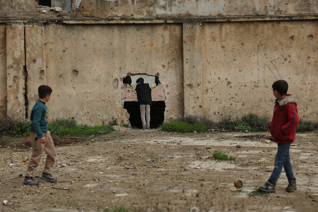 Youths play near a damaged school in the Kurdish-majority neighborhood of Sheikh Maqsoud, in Aleppo, Syria, Saturday, Feb. 14, 2026. (AP Photo/Ghaith Alsayed)