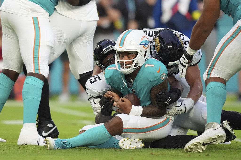 Miami Dolphins quarterback Tua Tagovailoa (1) falls on the field after he was sacked by Jacksonville Jaguars defensive end BJ Green II (95) during the first half of an NFL preseason football game, Saturday, Aug. 23, 2025, in Miami Gardens, Fla. (AP Photo/Rebecca Blackwell)