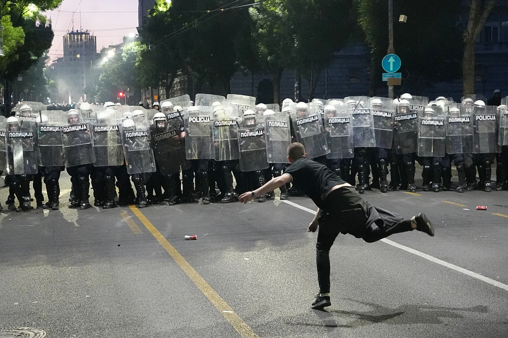 A man throws a cobblestone at riot police as clashes break out during a rally led by Serbia's protesting university students who are pushing for major political changes in the Balkan country run by President Aleksandar Vucic, in Belgrade, Serbia, Saturday, May. 23, 2026. (AP Photo/Darko Vojinovic)