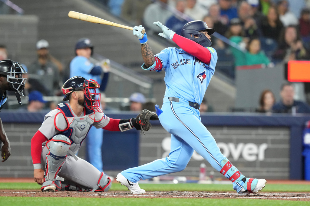 Toronto Blue Jays' Yohendrick Pinango (24) hits an RBI single in front of Boston Red Sox catcher Connor Wong (12) during the third inning of a baseball game in Toronto, Wednesday, April 29, 2026. (Chris Young/The Canadian Press via AP)