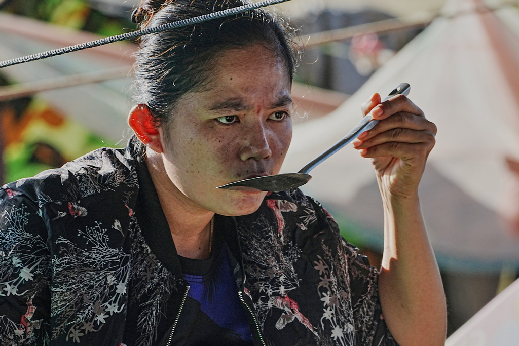 An evacuee tastes soup as she takes refuge in Banteay Menchey provincial town, Cambodia, Saturday, Dec. 13, 2025, after fleeing from home following fighting between Thailand and Cambodia. (AP Photo/Heng Sinith)