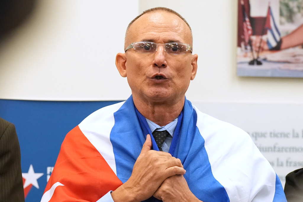 Cuban dissident Jose Daniel Ferrer holds his nation's flag over his shoulders as he gives a news conference in Miami, Florida, Monday, Oct. 13, 2025, the day he left Cuba for exile in the U.S. (AP Photo/Marta Lavandier)