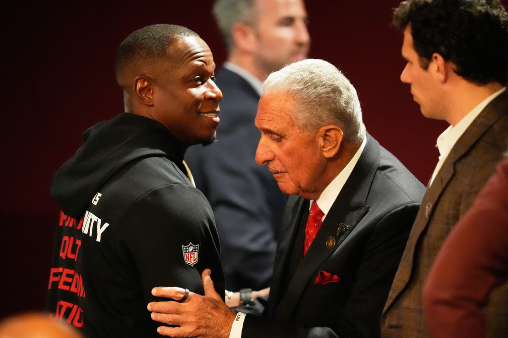 Arthur Blank, derecha, propietario de los Falcons de Atlanta, abraza al coach Raheem Morris después del partido de la NFL en contra de los Saints de Nueva Orleans, el domingo 4 de enero de 2026, en Atlanta. (AP Foto/Mike Stewart)
